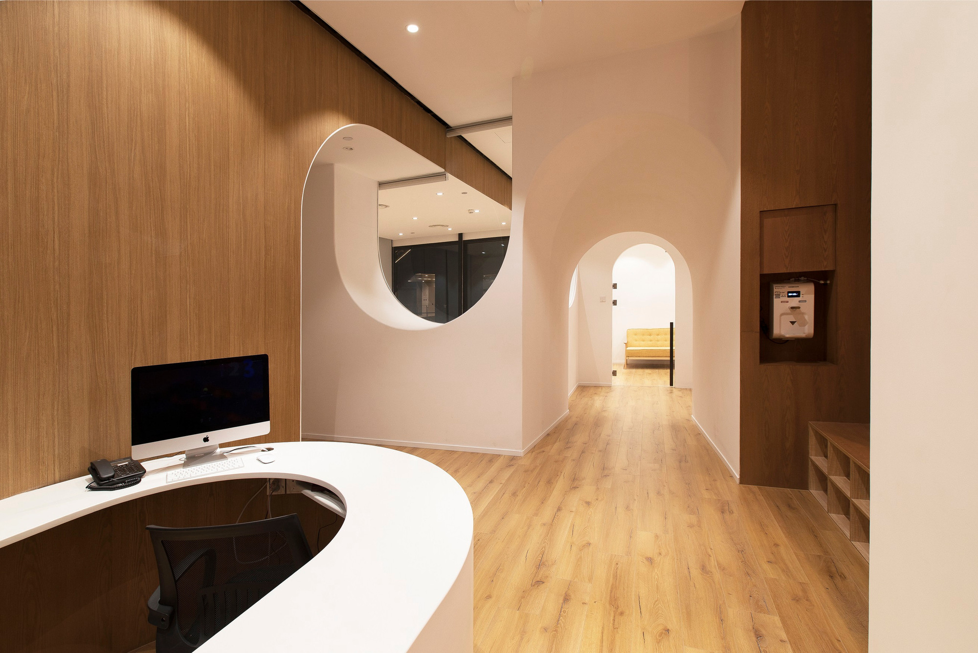 Completed reception area with a curved desk, timber lining and framed openings.