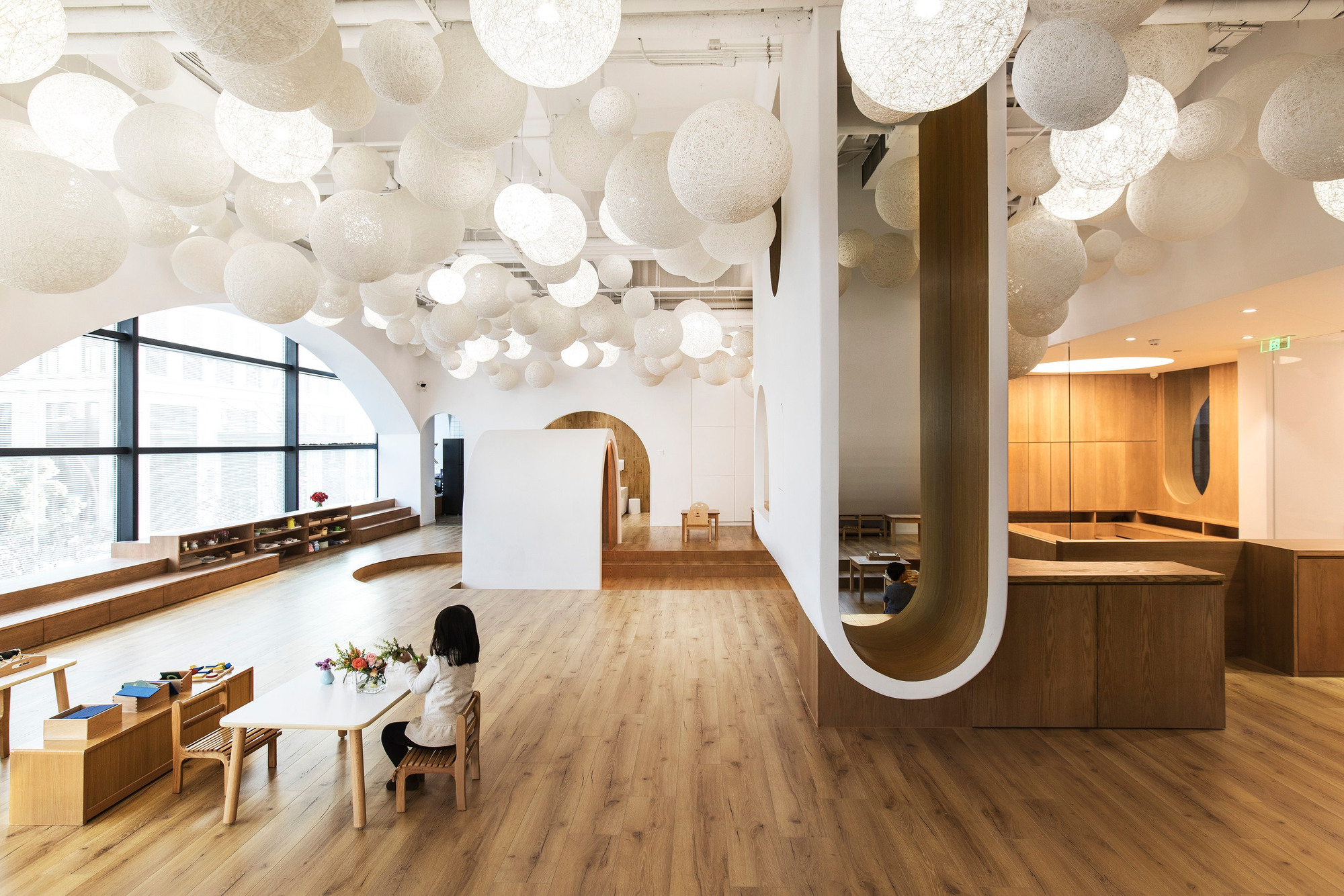 Completed shared learning interior, viewed toward the rounded opening and timber-lined activity area.