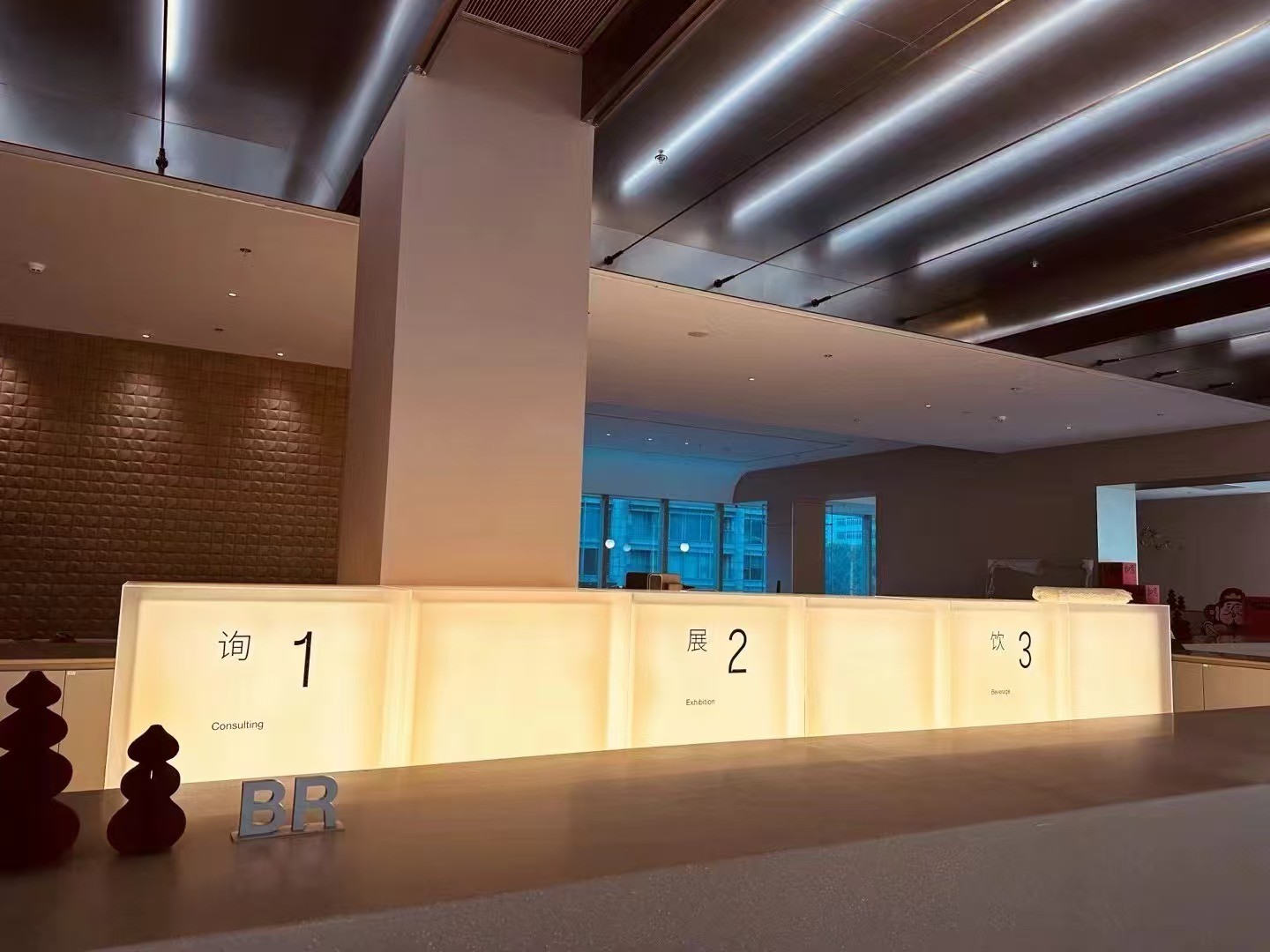 Illuminated counter panels identify consultation, exhibition and beverage functions.