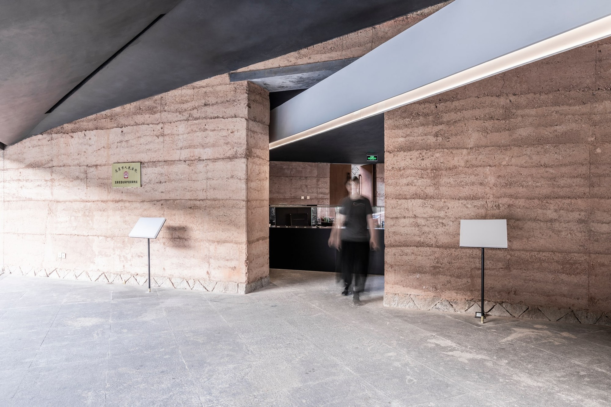 An opening in the rammed earth partitions frames the entrance to the display area.